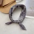 Vista detallada de un pañuelo de seda bohemio con estampados florales vintage y lunares - Gris