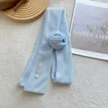 Detail of light blue knitted floral scarf featuring a white Hand Made fabric label - 3D Rose Flower Style / Azure Blue