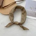 Détail d'un foulard en soie vintage avec imprimé floral marron sur socle en bois - Brun Café Floral