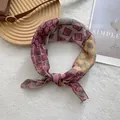 Detalle de pañuelo de seda vintage con estampados paisley sobre fondo blanco texturizado - Rojo