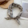 Detalle de un pañuelo floral con pétalos marrones sobre una base gris suave - 70x70cm / Gardenia