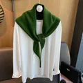 Details des dunkelgrünen Strickschals aus Wolle mit Goldknopf über weißem Top - Grün