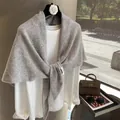Detalle de chal de lana gris claro drapeado sobre un top blanco con iluminación natural suave - Gris claro
