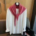 Detail eines Wollstrickschals mit runden Metallakzenten über weißem Langarmshirt - Fuchsia