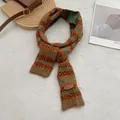 Detailopname van Fair Isle gebreide sjaal met golfpatronen en lederen merklabel - koffiekleur
