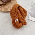 Dettaglio della sciarpa in maglia caramello con trama a trecce e etichetta del marchio - Arancione Vivace