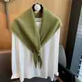 Detail eines grünen Strickschals über einem weißen Langarmshirt auf einem Blumenbügel - Gelbgrün