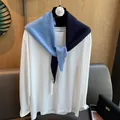 Detailansicht eines zweifarbigen Strick-Halstuchs mit Wollstruktur und Metallanhänger - Navy und Meersalzblau