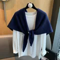 Detalle de chal de punto azul oscuro anudado sobre una camiseta blanca de manga larga para mujer - Azul marino