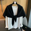 Detail of the black hollow-out knitted triangle shawl styled over a white long-sleeve T-shirt - Black