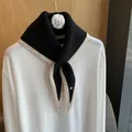 Detail shot of the knitted texture and white contrast trim on a black triangular scarf - Black