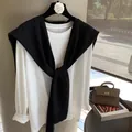Detail of a chic black knitted shawl layered over a white long-sleeve T-shirt - Black