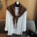 Detailed view of dark brown hollow knit wool scarf layered over a white long sleeve tee - Coffee