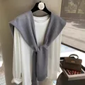 Detail of grey knitted shawl styled over white long-sleeve tee on a designer hanger - Gray