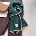 Detailed texture of dark green knit wool scarf with beige contrast trim and white label - Christmas Green