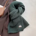Detailed close-up of dark green wool blend scarf with a decorative woven label - Korean Forest Green