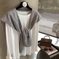 Dettaglio dello scialle in maglia di lana grigia sopra una t-shirt bianca a maniche lunghe - Grigio chiaro