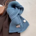 Close-up of winter scarf wool blend fabric with brand label and care tag detail - Sea Salt Light Blue