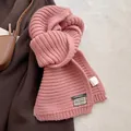 Detail of pink wool blend chunky knit scarf featuring a brand label and material tag - Sakura Pink