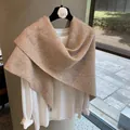 Detail showing soft texture of light khaki wool blend knitted shawl on a camellia hanger - Oatmeal