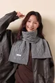 Detail of grey 100% merino wool scarf showing classic cable knit texture and material tag - Wool Gray