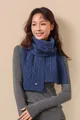 Detail of dark blue merino wool scarf featuring classic cable knit pattern and gold plate - Blue