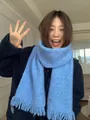 Close-up of light blue wool blend scarf featuring delicate sequins and tassel edges - Blue