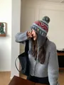 Close-up of winter knit hat with colorful pom-pom and Nordic geometric jacquard pattern - Gray