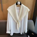 Détail d'un châle en laine blanc cassé avec maille en chevrons et boucle décorative - Crème