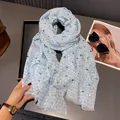 Close-up of light blue scarf with gold foil hearts and tassel edge on a black tray - 180x60cm / Light Blue