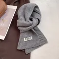 Detailed texture of grey chunky rib knit wool scarf with a minimalist brand label - Light Gray
