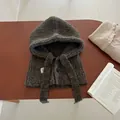 Detail of dark brown knitted balaclava with button and red blue logo on wooden desk - Coffee Brown