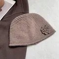 Detailed texture of brown crochet knit beanie with side flower accent and soft wool finish - Khaki