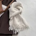 Detail of cream knit scarf with shiny sequins and metal brand logo tag in macro view - Marled Beige