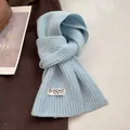 Detailed texture of light blue knitted wool scarf featuring a white woven brand label - Azure Blue