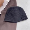 Detail of hand-crocheted black knit beanie featuring a floral accent on winter wool fabric - Black
