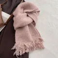 Close-up of pink wool blend knit scarf featuring fringe tassels and a silver logo tag - Pink