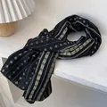Détail d'une écharpe en coton bleu marine avec motifs floraux vintage et plis doux - Noir