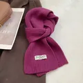 Close-up of deep magenta ribbed knit wool scarf texture with elegant brand label - Raspberry Red