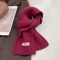 Detailed view of burgundy ribbed knit wool scarf featuring a woven minimalist brand tag - Burgundy