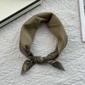 Primer plano de un pañuelo de seda verde oliva con elegantes patrones geométricos - Caqui