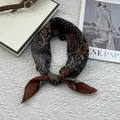 Macro detail of knotted vintage paisley silk scarf with coffee and blue floral patterns - Orange Coffee