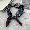Detalle de un pañuelo de seda anudado con estampado paisley en azul marino y crema - 70x70cm / Negro