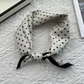 Detailed view of white polka dot silk scarf with black borders and knotted styling - 70x70cm / Small White Polka Dot