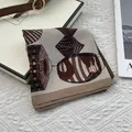 Detailed shot of vintage paisley square scarf on white gift box with silk texture - Khaki