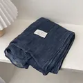 Detail van zachte donkerblauwe linnen sjaal met wafeltextuur en een minimalistisch label - 180*70cm / Donkerblauw
