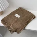 Close-up of brown linen scarf with colorful stitching and fabric label on a white shelf - 180*70cm / Camel