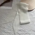 Détail d'un foulard plissé blanc montrant la texture froissée sur fond de dentelle - Ivoire