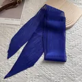 Détail d'une écharpe longue plissée bleu roi sur planche en bois et fond en tricot - Bleu