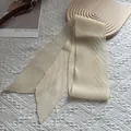 Detail eines plissierten beigen Schals auf Holztablett mit dekorativer Kunstkarte - 130*9cm / Gebrochenes Weiß